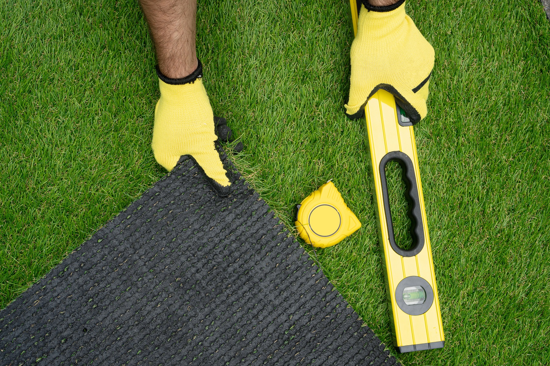 Man's hands with the artificial grass roll and tools